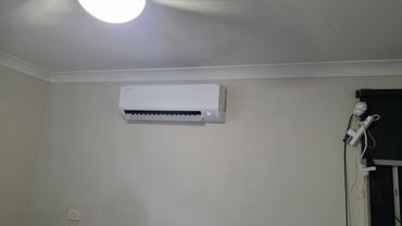 White Samsung air conditioner mounted on a beige wall.