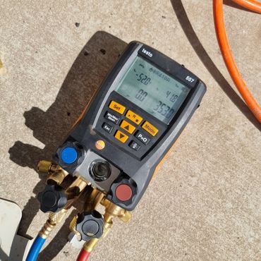 Digital HVAC manifold gauge showing temperature and pressure readings.