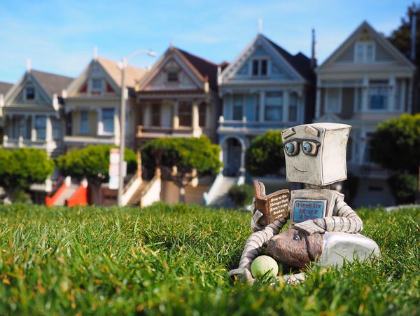 a robot sitting on the grass and reading 
