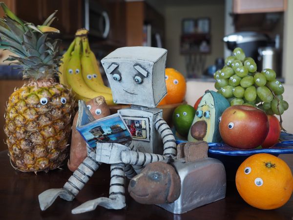 Melvin robot sitting with fruits and reading 