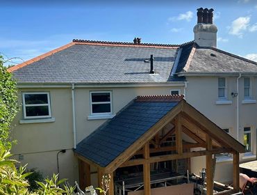 House with a wooden-framed extension under construction in a garden.