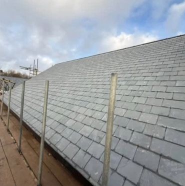 Newly installed slate roof with scaffolding around it.