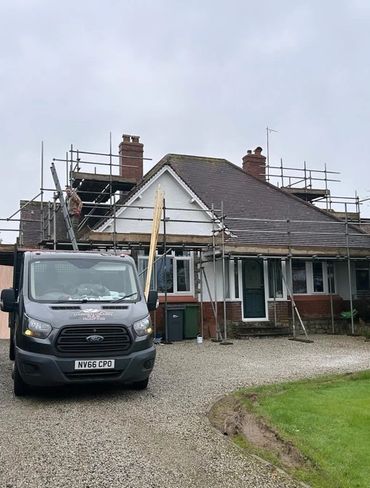 House under renovation with scaffolding and a work van parked outside.