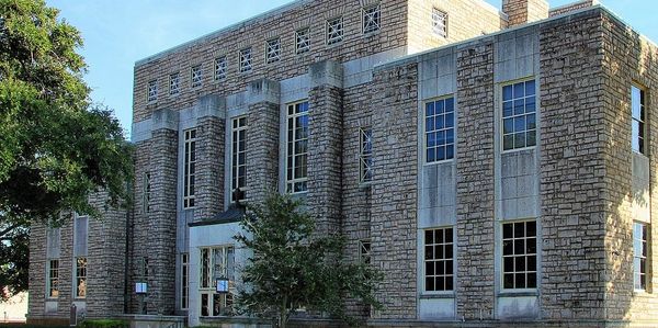 Historic stone building with large windows and lush green surroundings. Cherokee County Courthouse.