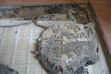 Tiles installed onto newspaper causing the floor to fail, showcasing poor understanding of tiling