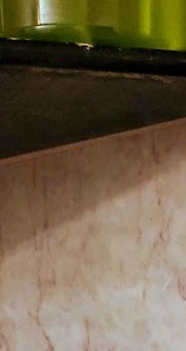 Close-up of stained and cracked beige marble tiles with grout lines.