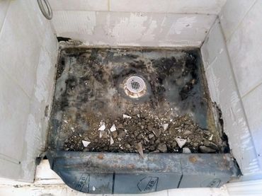Black moldy shower pan liner caused by water damage, showcasing bad craftsmanship and poor quality