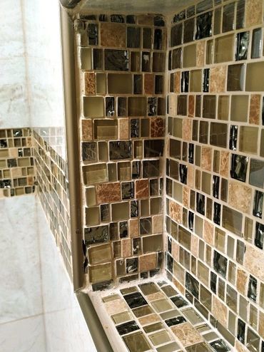 A poorly crafted shower niche featuring uneven mosaic tiles, highlighting flaws in workmanship
