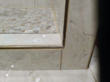 Poorly installed shower curb, revealing uneven edges and inadequate sealing against water leakage