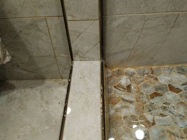 Shower pan installation appears faulty with visible misalignment and gaps
