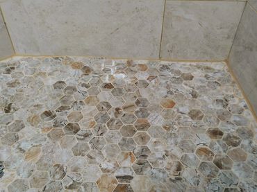 Shower pan featuring uneven mosaic tile installation, indicating subpar craftsmanship