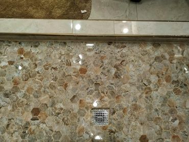 Unevenly installed mosaic tile in a shower pan, highlighting signs of poor craftsmanship