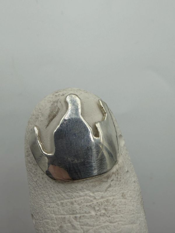 Polished silver crown ring on a textured surface.