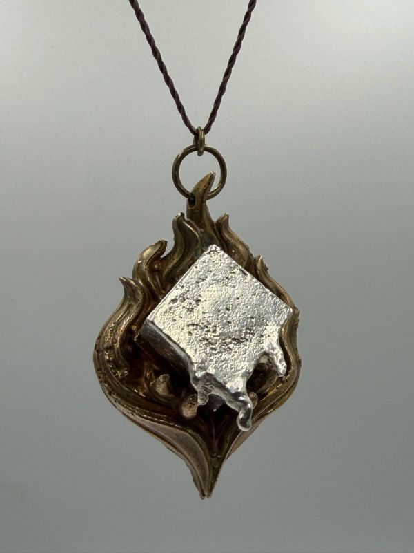 Pendant with flame design and silver square element.