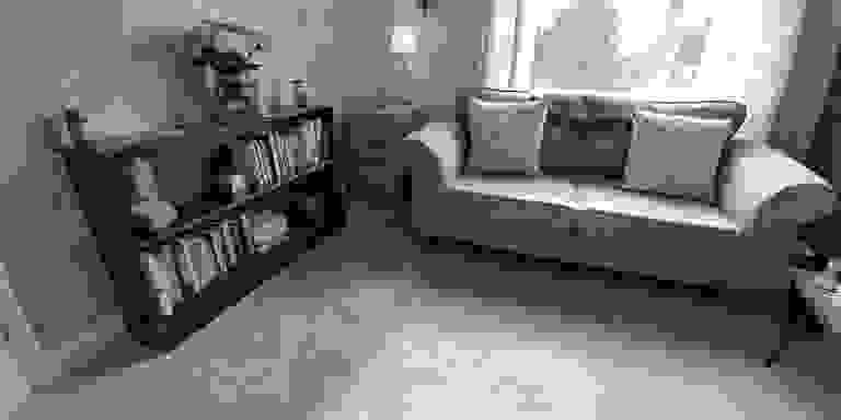 A bright airy therapy room with a light coloured sofa on the right, and a bookcase on the left.
