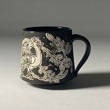 Black and white mug with peacock and garden design. Black handle, base and interior.