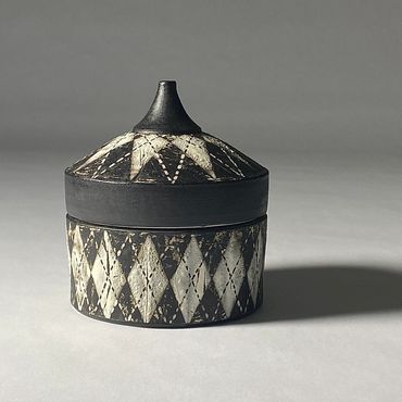Black and white ceramic box with argyle design. Black rim and knob.