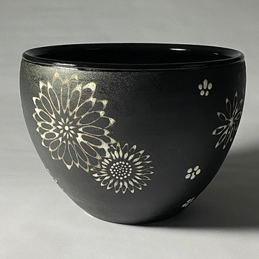 Black ceramic serving bowl with white flower mandala design. Gloss black interior.