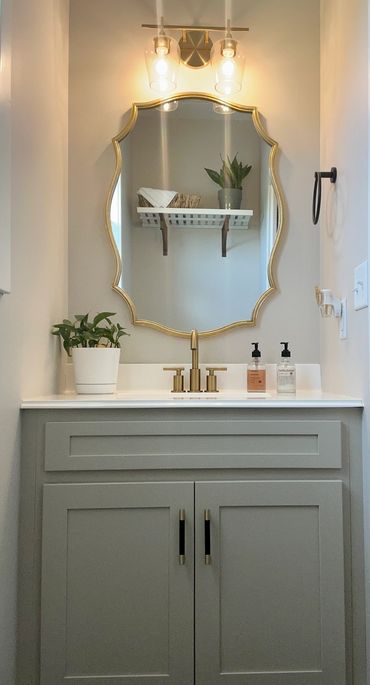 Elegant bathroom vanity with gold-framed mirror and modern fixtures.