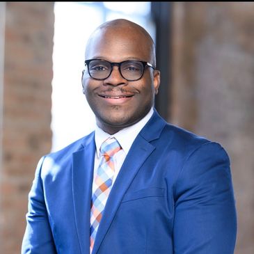 Smiling man in blue suit and glasses.