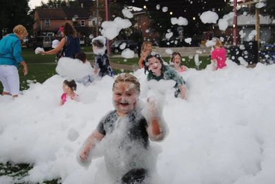 Children smiling and playing in foam.