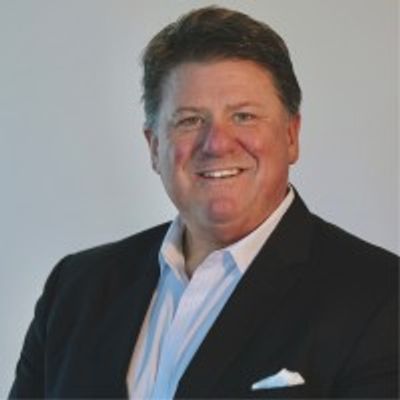 Smiling man in a dark suit with a white shirt and pocket square.