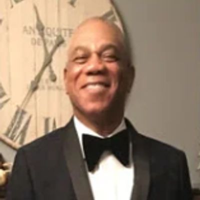 Man in a tuxedo smiling warmly.