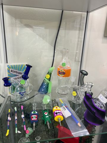 Glass smoking pipes and accessories displayed with price tags in a glass case.