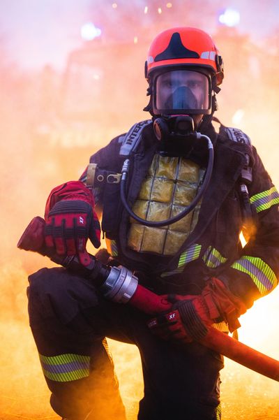 Firefighter wears Inuteq PCM CoolOver 21C cooling vest under jacket mask fire in background