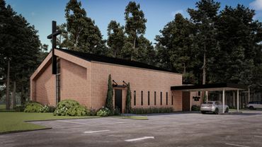 Modern brick church with a large cross and parking area surrounded by trees.