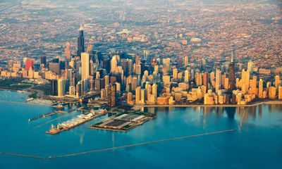 Aerial view of a city skyline by a large body of water during sunset.