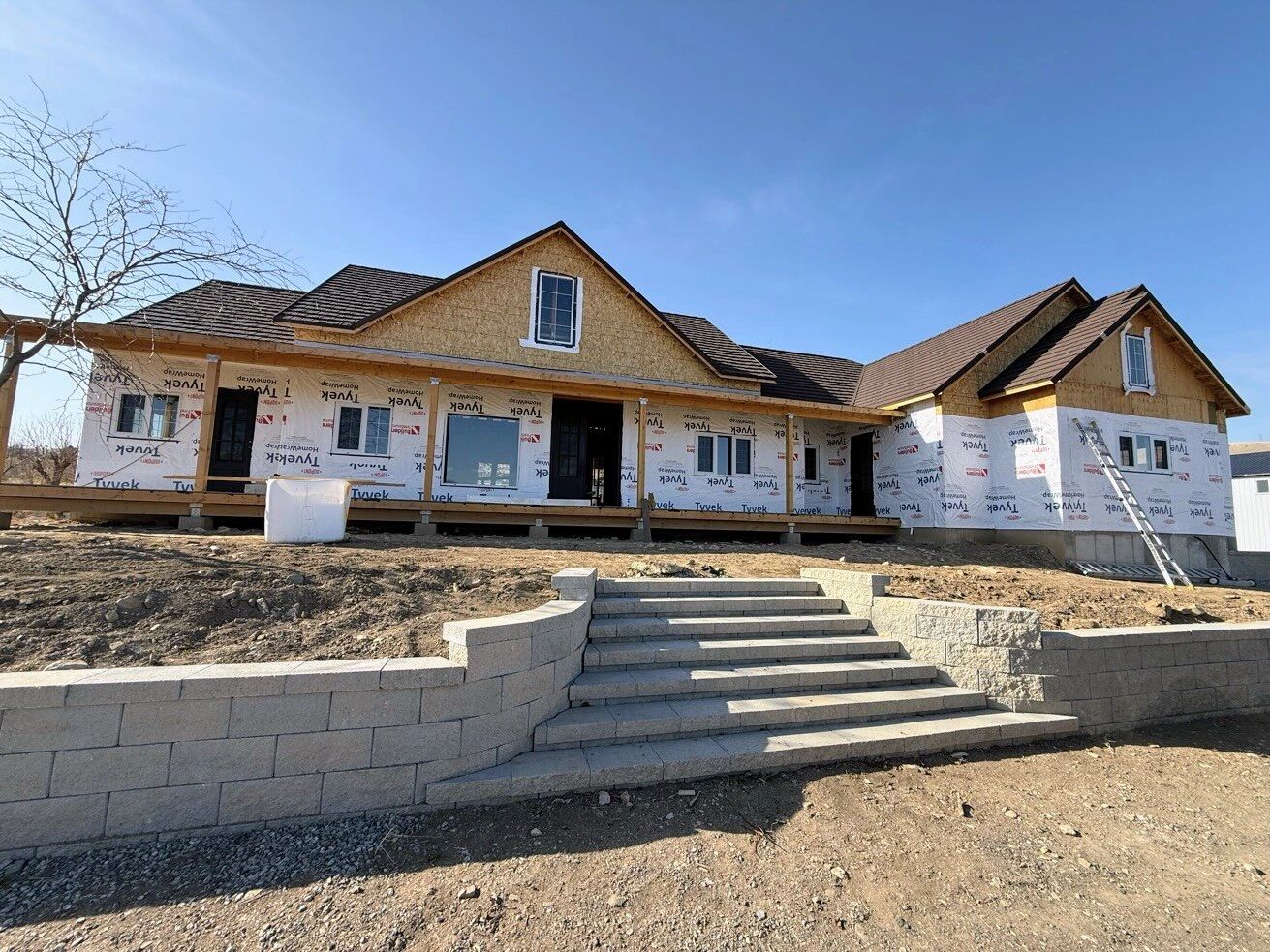 A large house under construction with a stone staircase and retaining wall.