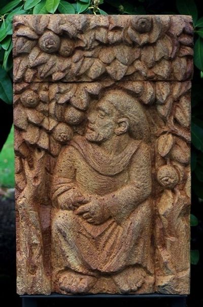 carved relief sculpture of St Francis in an orchard