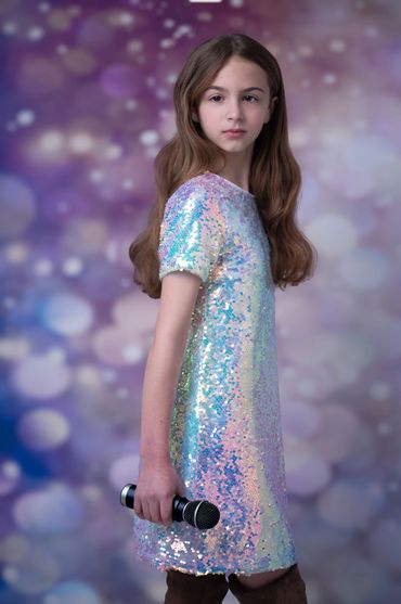 tween girl in sparkly dress powerfully standing with microphone