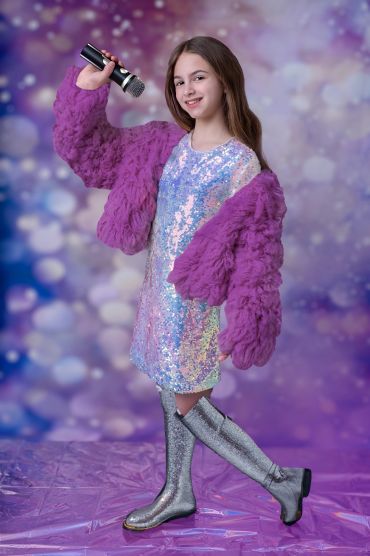 tween girl with microphone wearing sparkly dress and boots