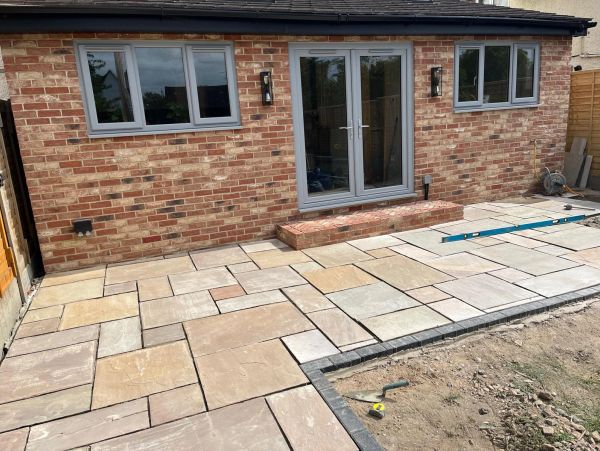 Backyard patio with newly laid stone tiles and brick house.