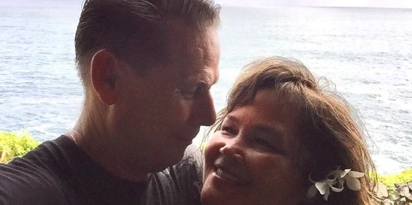 Couple sharing a tender moment by the ocean with a flower in her hair.