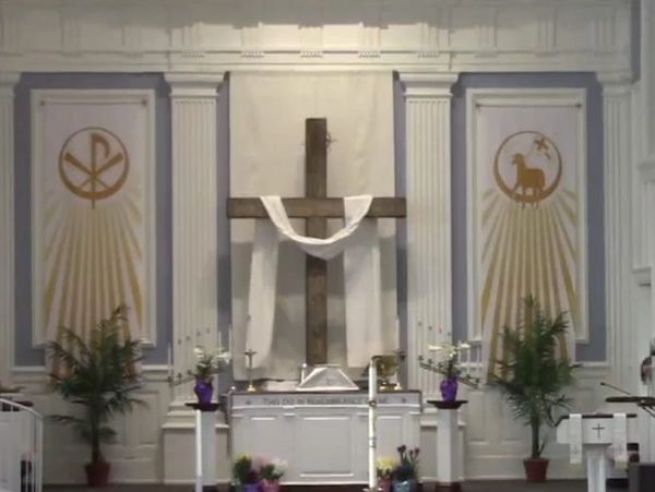 Interior view of a church altar with a wooden cross and religious symbols.