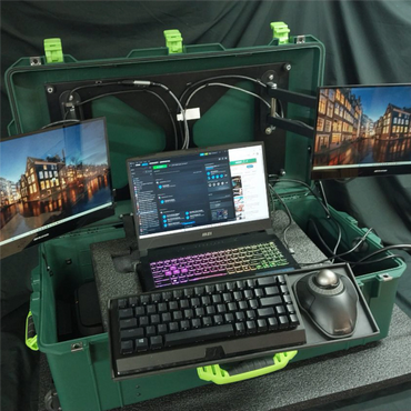 Portable tech setup with dual monitors, laptop, and keyboard in a rugged case.