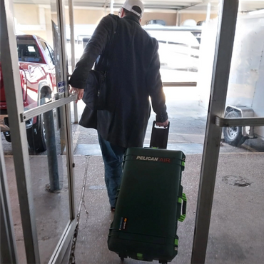 Person pulling a large Pelican Air case through a doorway.