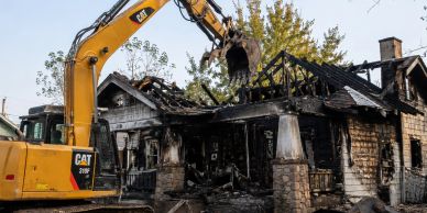 Excavator demolishing a burnt house.