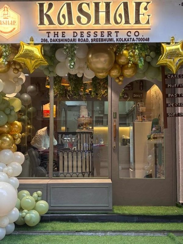 Front View of "Kashae" The Dessert Co. decorated with gold, white, and green balloons