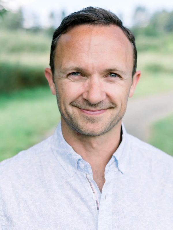 Smiling man in a light shirt outdoors.