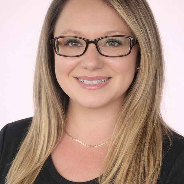 Smiling woman with glasses and straight hair.