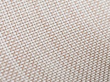 Close-up of a beige woven fabric texture with a tight, intricate pattern.