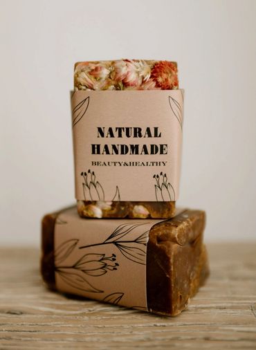 Two stacked bars of natural handmade soap with floral designs on the packaging.