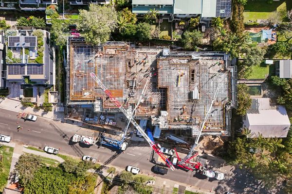 Aerial view of a busy construction site surrounded by greenery and residential buildings.