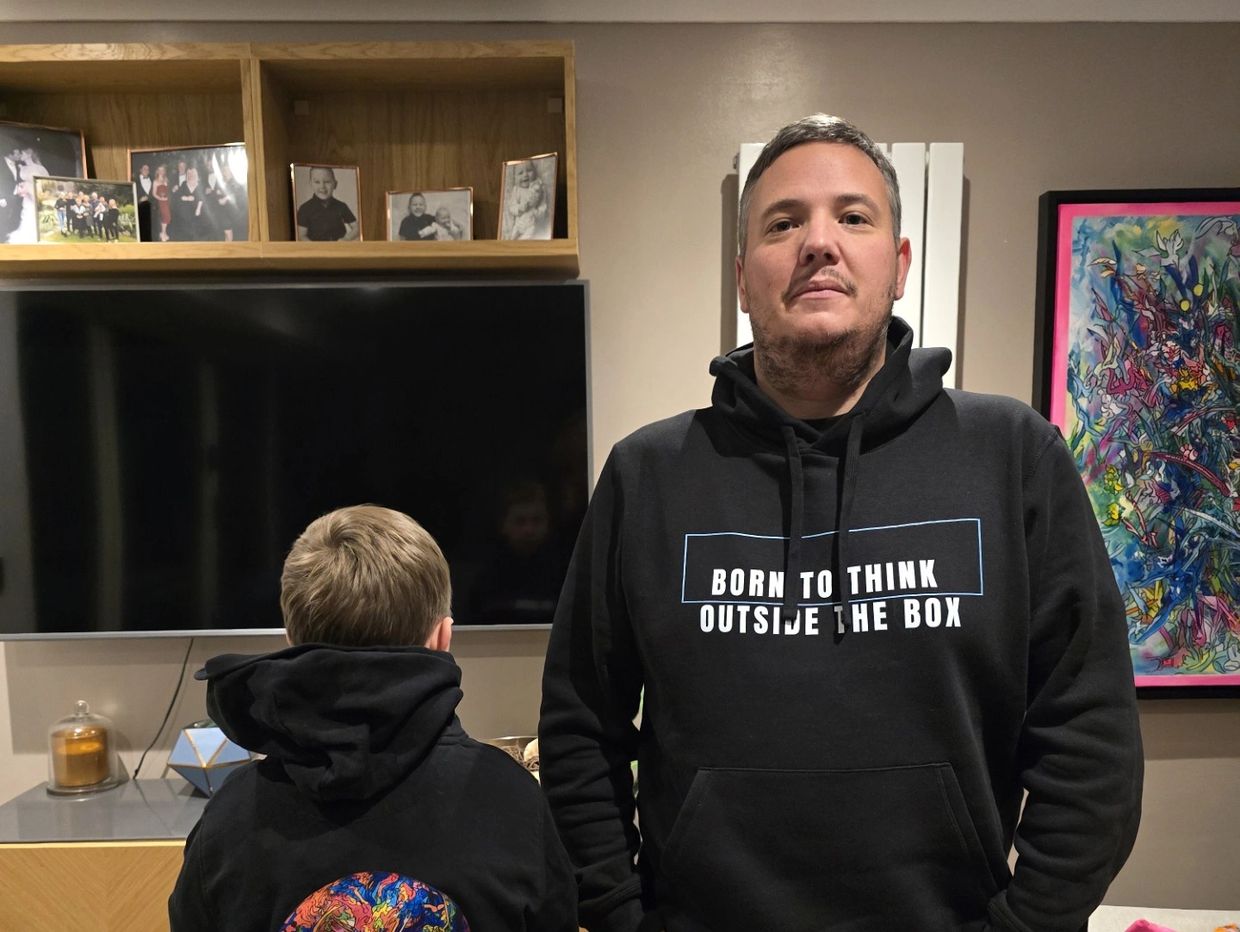 A man and child in matching black hoodies in a cozy living room.