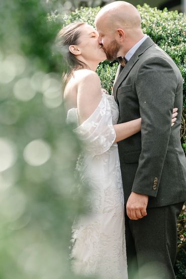Bride and groom sharing a tender kiss outdoors on their wedding day.