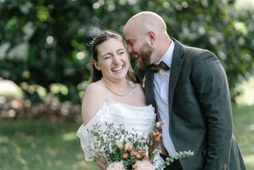 A joyful bride and groom share a loving, laughter-filled moment outdoors.